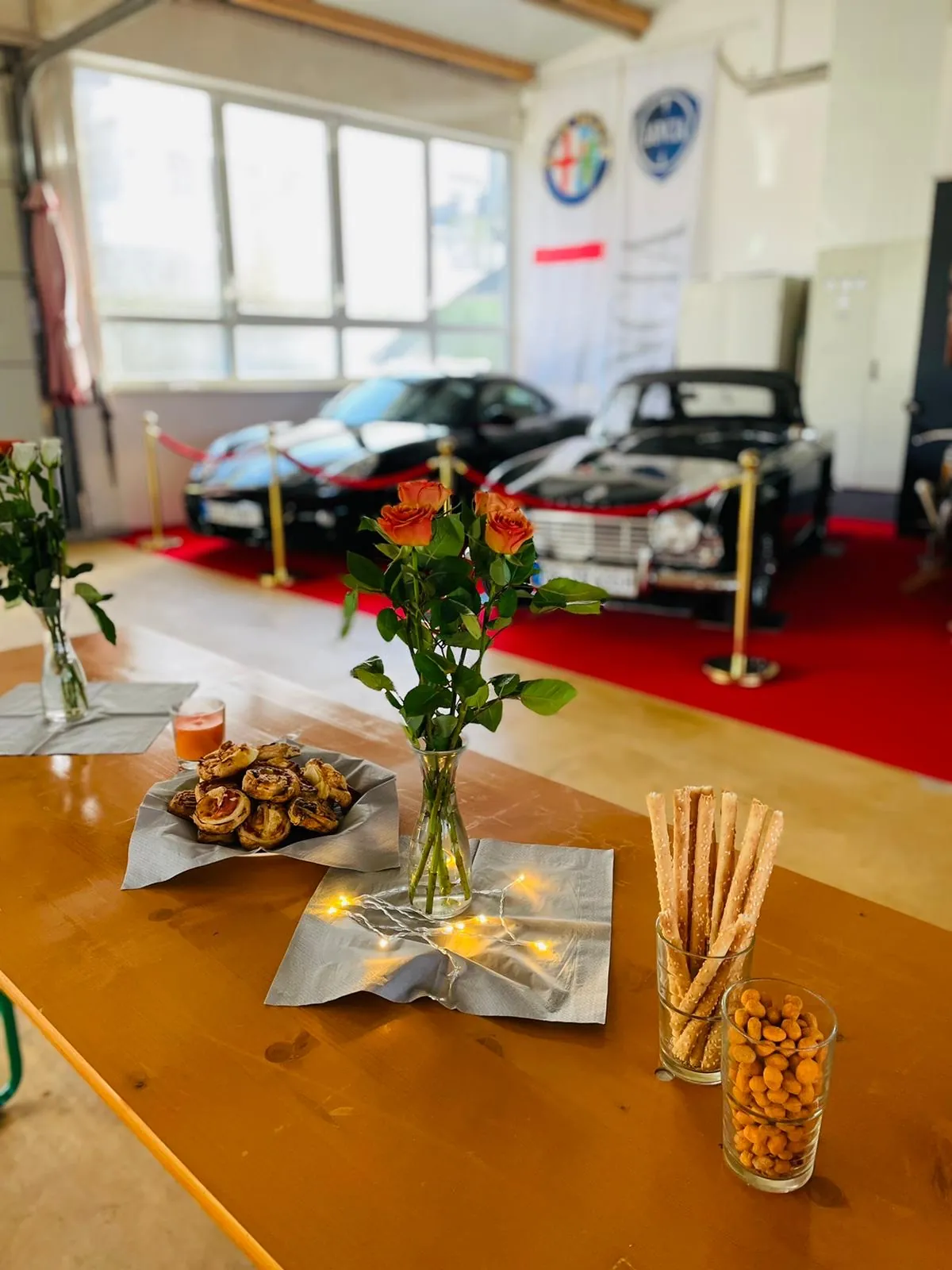 Empfangstisch mit Blumen, dahinter klassische Fahrzeuge